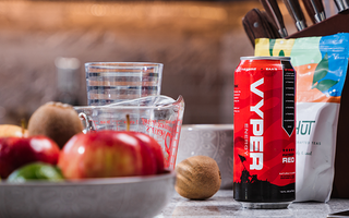 Red and black vyper energy can on kitchen counter with bowl of fruit, measuring cup, and knives